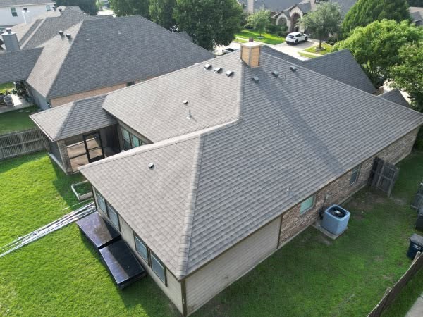 Completed asphalt shingle roof on a single-story stone home in Weatherford, TX