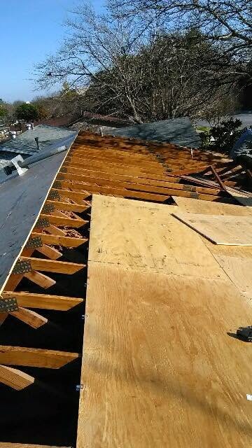 Damaged roof decking removed, exposing the rafters, during a roof repair