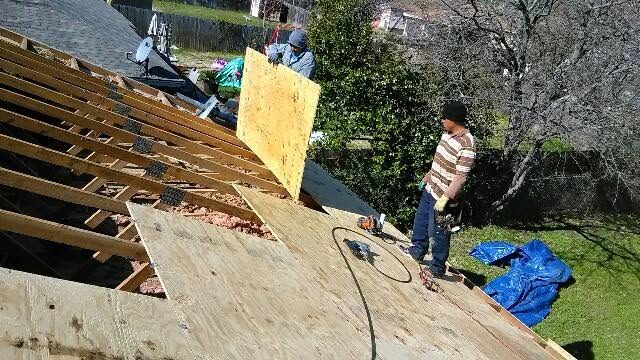 New decking being laid over exposed rafters during a roof repair
