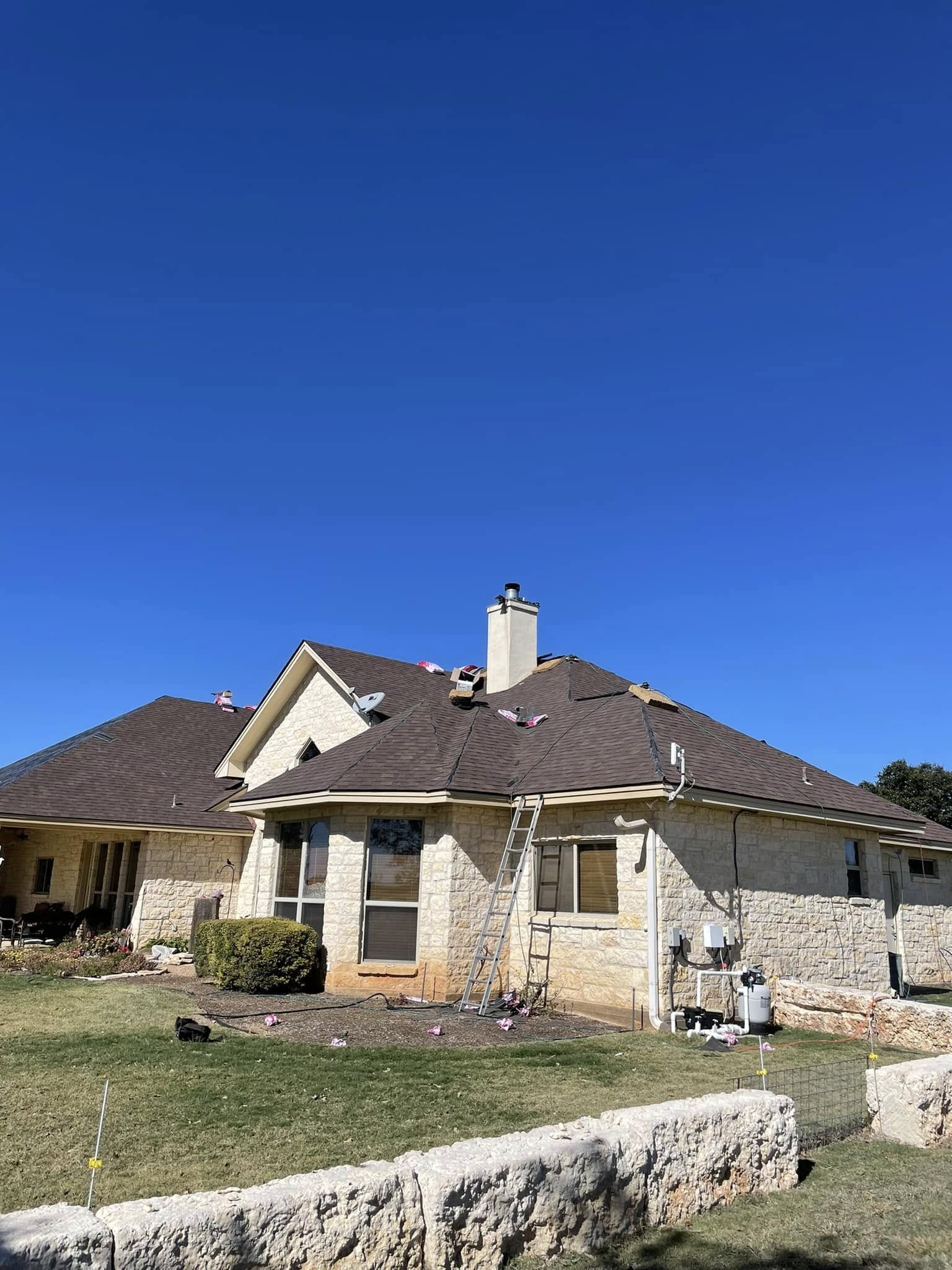 Completed roof replacement on a stone home with a clean, tidied site