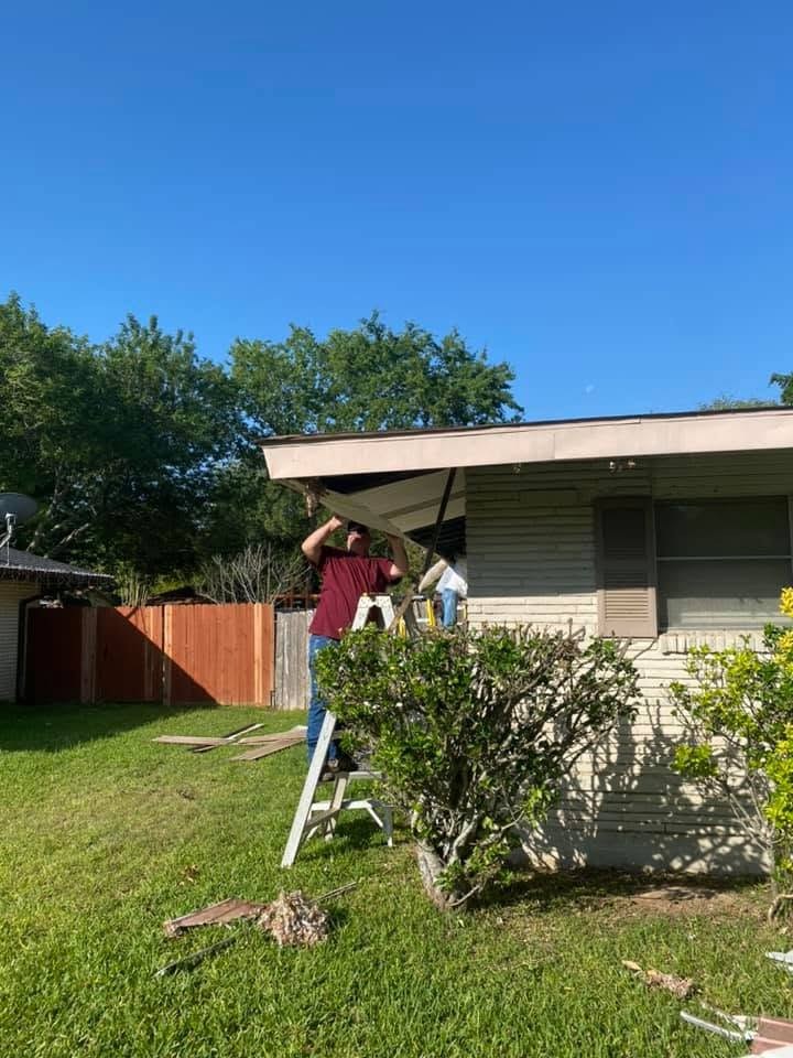 Crew member on a ladder working on the side elevation during a window and siding replacement